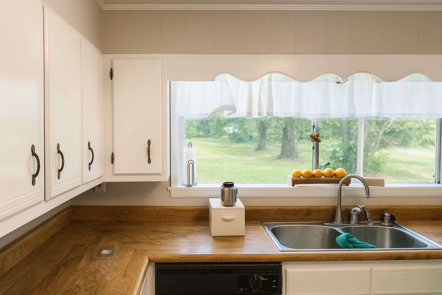 Tidy kitchen with sink, side cabinets, and windows overlooking the sidewalk