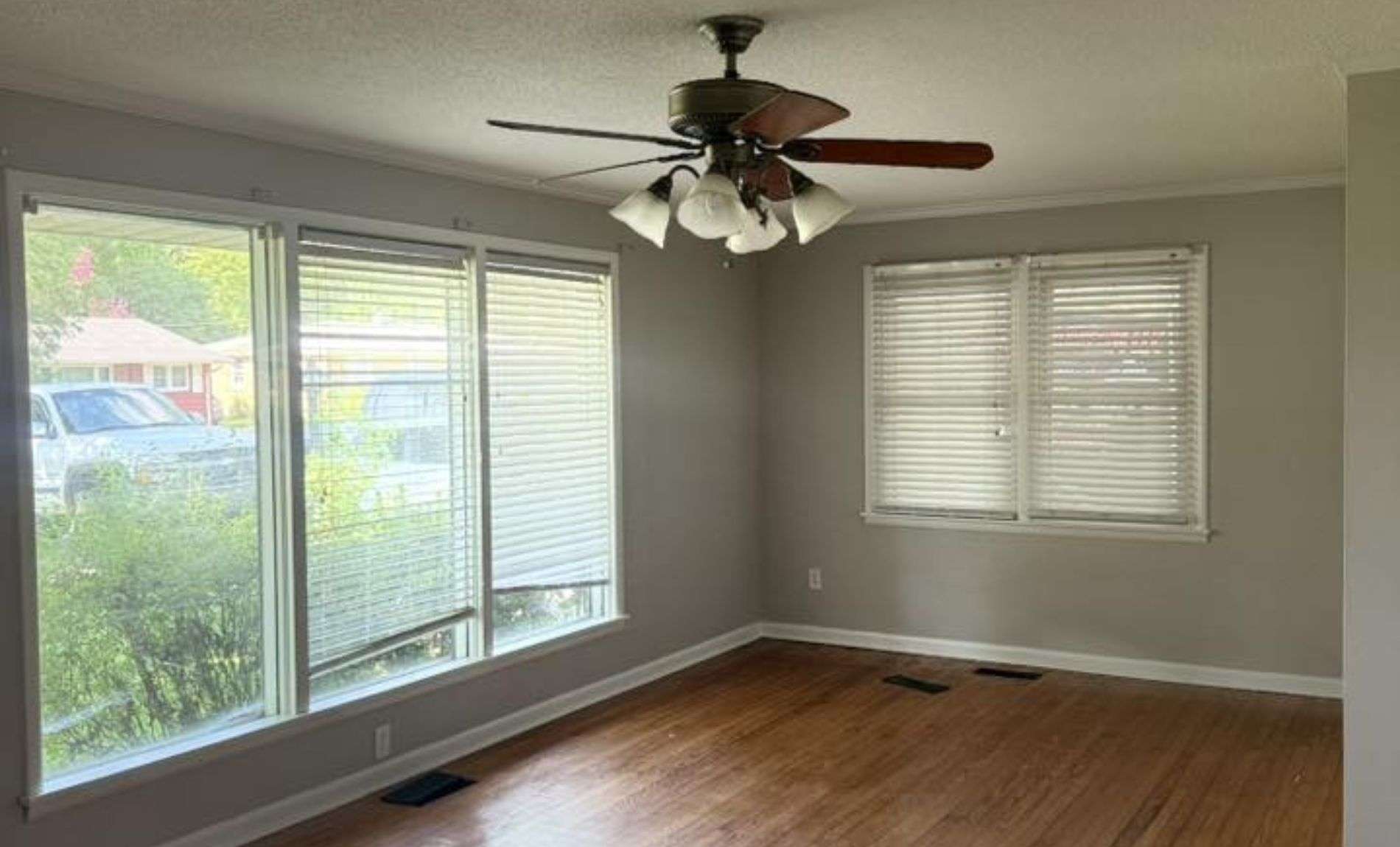 Interior of a room with large windows with blinds and wooden flooring