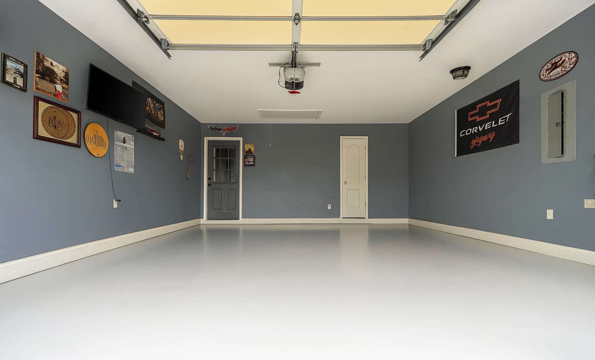 Interior of a residential property with white floor, gray walls, picture frames, and TV